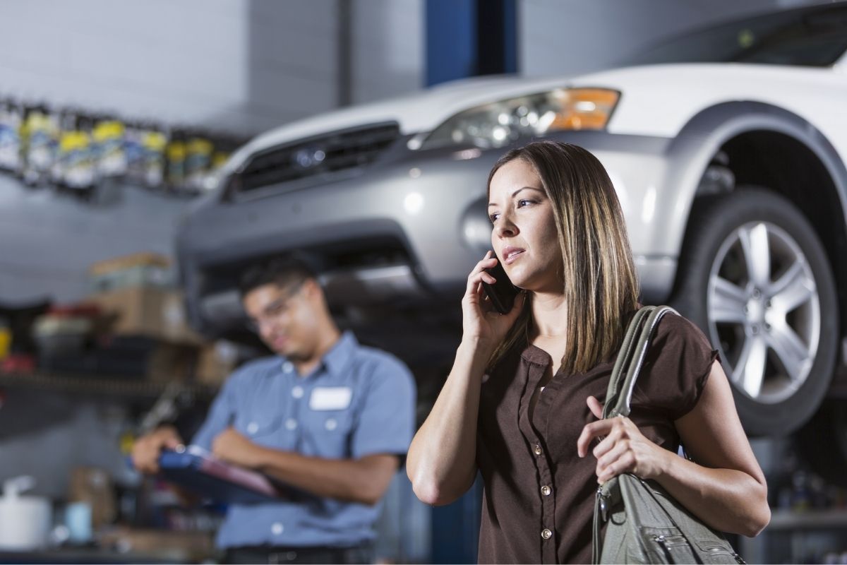 Uma mulher com carro na oficina fala ao celular